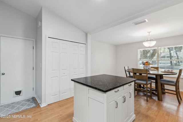 96033 River Marsh Bnd, Fernandina Beach, FL 32034 - kitchen with light wood-style floors, white cabinetry, a center island, hanging light fixtures, and baseboards