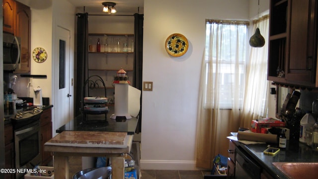 kitchen featuring baseboards, appliances with stainless steel finishes, dark countertops, and tile patterned floors