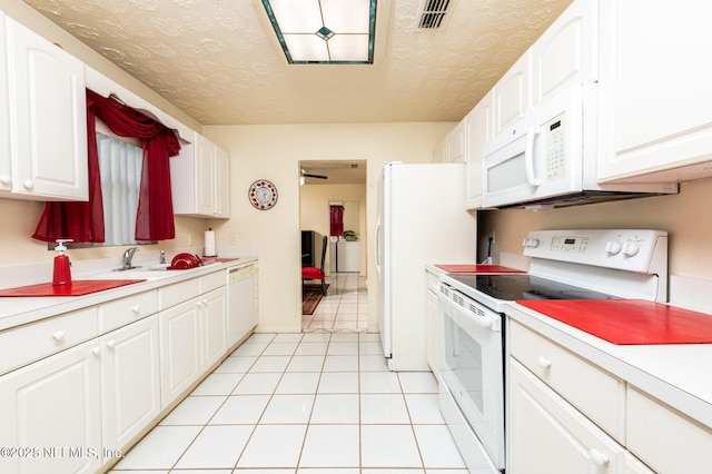 kitchen with white cabinets, light countertops, a sink, and white appliances