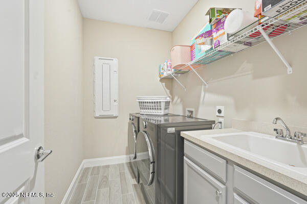 73 Lily Landing Dr, Saint Augustine, FL 32092 - washroom with washer and clothes dryer, a sink, light wood-type flooring, baseboards, and cabinet space