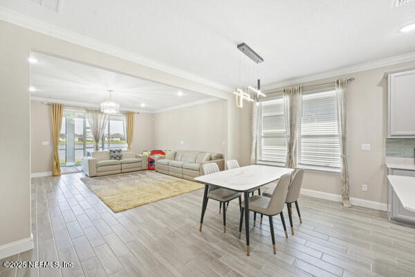 73 Lily Landing Dr, Saint Augustine, FL 32092 - dining area with light wood-style flooring, crown molding, baseboards, recessed lighting, and a notable chandelier