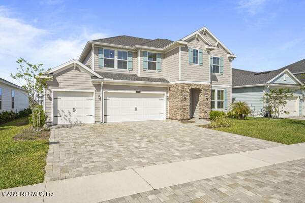 73 Lily Landing Dr, Saint Augustine, FL 32092 - view of front of house with stone siding, a front yard, decorative driveway, and a garage