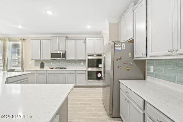 73 Lily Landing Dr, Saint Augustine, FL 32092 - kitchen featuring decorative backsplash, crown molding, stainless steel appliances, recessed lighting, and light stone counters