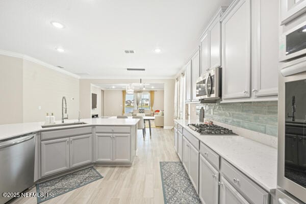 73 Lily Landing Dr, Saint Augustine, FL 32092 - kitchen featuring crown molding, light countertops, backsplash, a sink, and stainless steel appliances