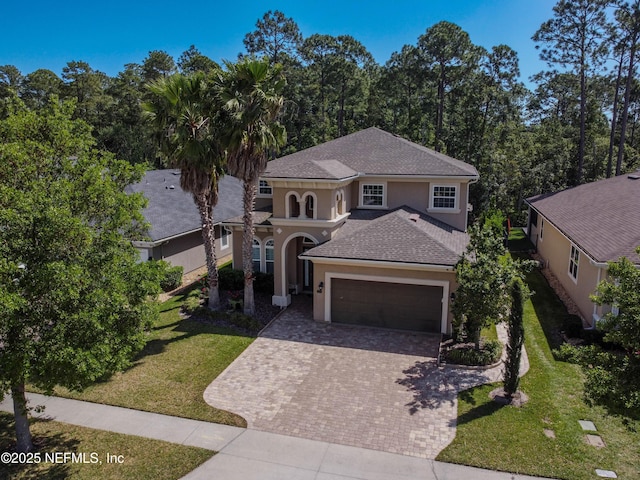 mediterranean / spanish house featuring a garage, a front yard, decorative driveway, stucco siding, and a shingled roof