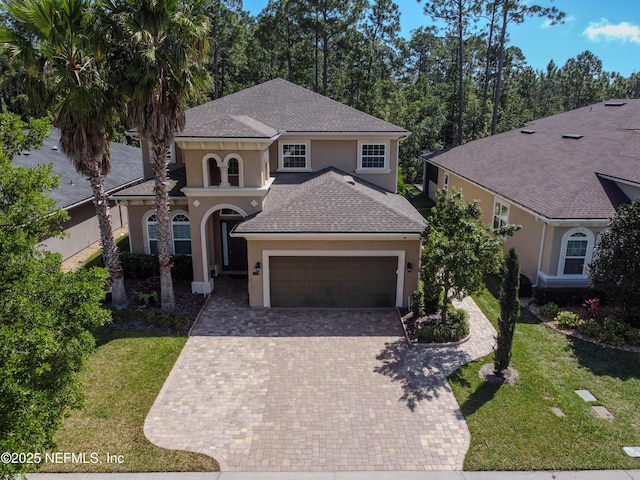 mediterranean / spanish house with a garage, decorative driveway, stucco siding, and a front yard