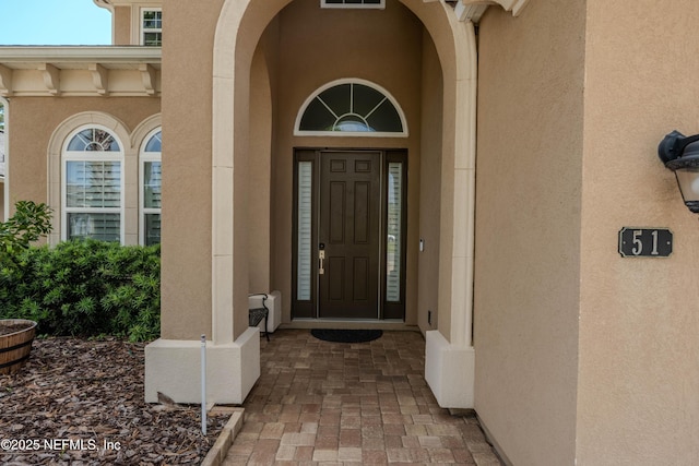 view of exterior entry with visible vents and stucco siding