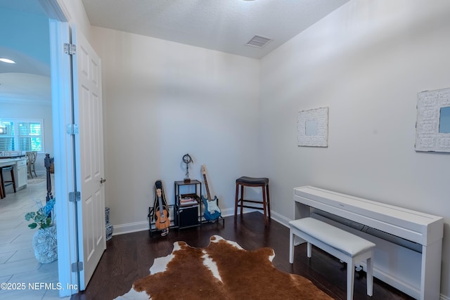 miscellaneous room with arched walkways, baseboards, visible vents, and wood finished floors