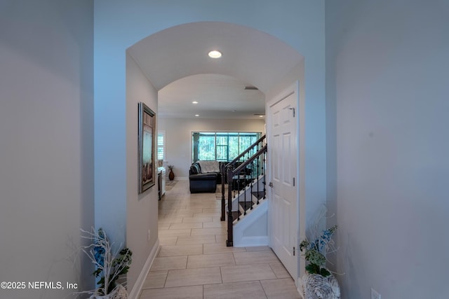 hall featuring recessed lighting, arched walkways, stairs, and baseboards