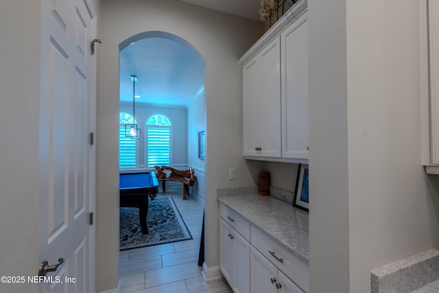 corridor featuring light tile patterned floors and arched walkways