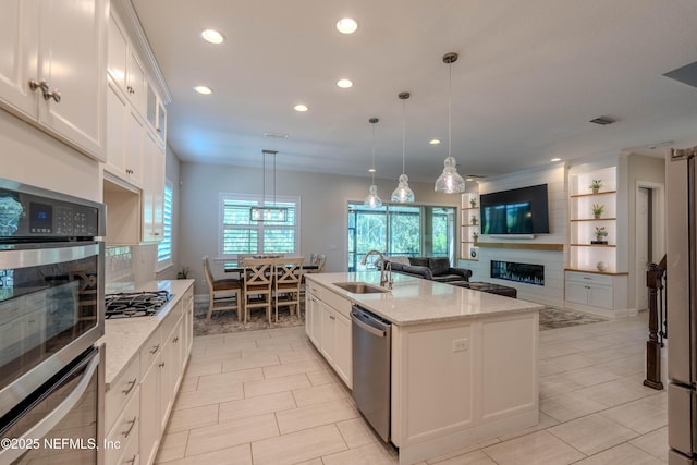 kitchen with appliances with stainless steel finishes, a fireplace, a sink, light stone counters, and recessed lighting
