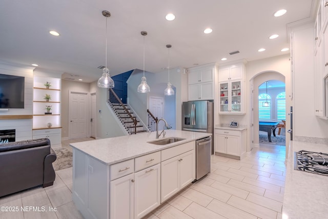 kitchen featuring a sink, arched walkways, stainless steel appliances, open floor plan, and white cabinetry