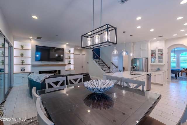 dining space with a fireplace, arched walkways, recessed lighting, visible vents, and stairway