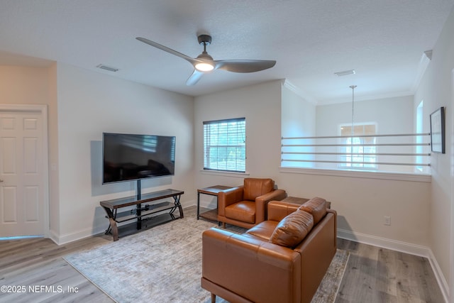 living area with baseboards, ceiling fan, and wood finished floors