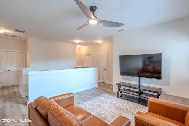 living area with baseboards, a ceiling fan, light wood-style flooring, and visible vents