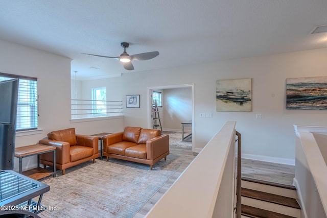 living room with plenty of natural light, a ceiling fan, and wood finished floors