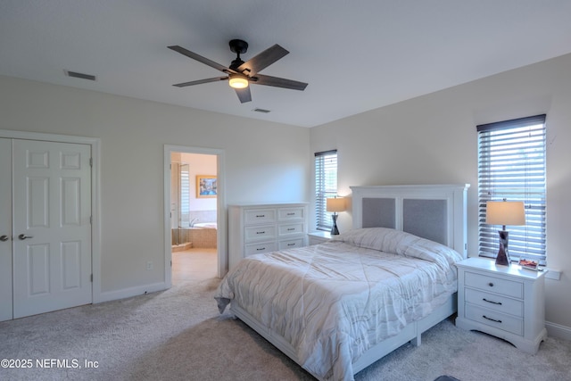 bedroom with baseboards, light carpet, ensuite bath, and visible vents