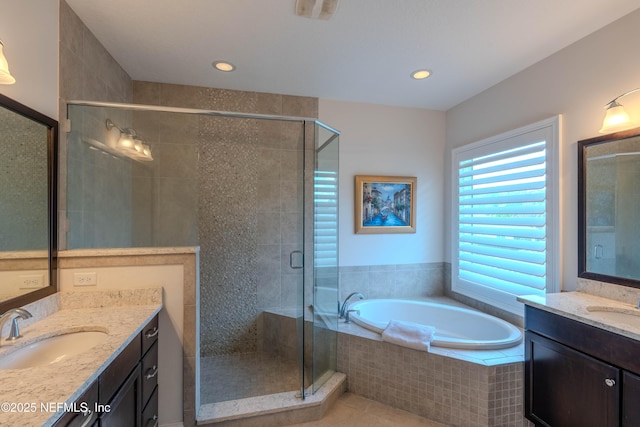 full bath with a sink, a stall shower, a bath, and two vanities