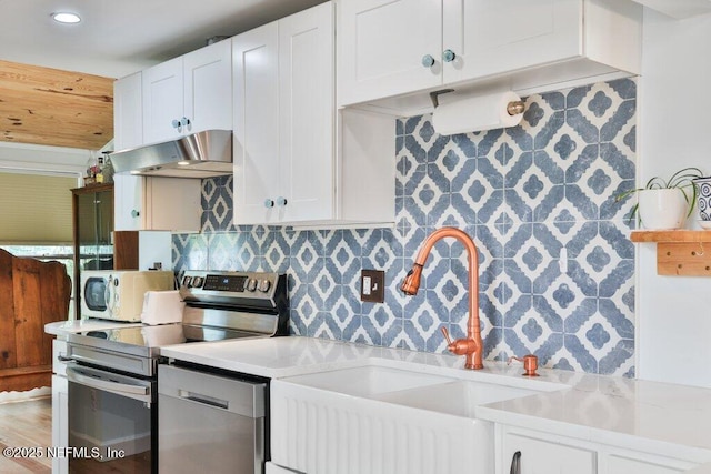 6960 Charles St, Saint Augustine, FL 32080 - kitchen with white cabinets, under cabinet range hood, light countertops, a sink, and stainless steel appliances