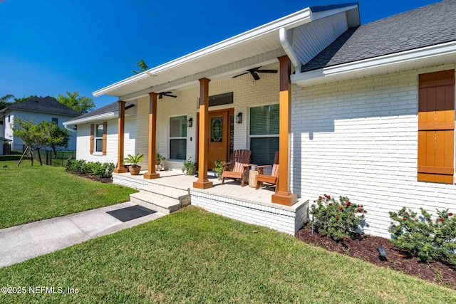 view of front of house with a porch, ceiling fan, a front lawn, and brick siding