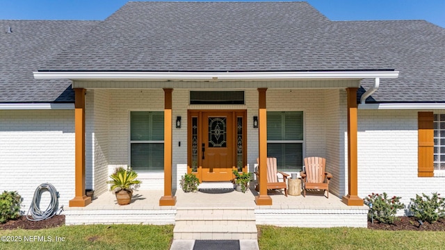 property entrance with brick siding, roof with shingles, and covered porch