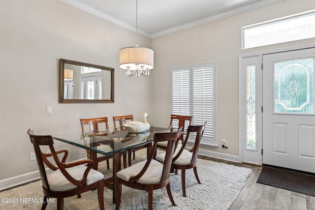 dining area with a chandelier, crown molding, wood finished floors, and baseboards