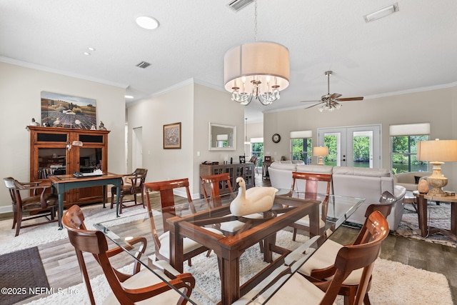 dining space with ceiling fan with notable chandelier, wood finished floors, ornamental molding, and visible vents