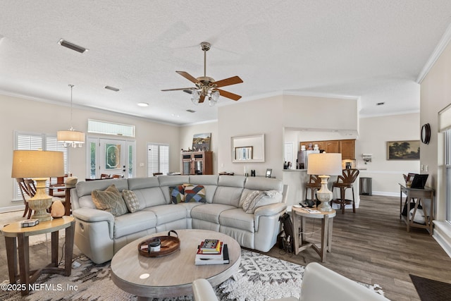 living room with crown molding, a ceiling fan, dark wood-style floors, and a textured ceiling