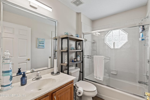 full bathroom featuring visible vents, combined bath / shower with glass door, toilet, a textured ceiling, and vanity