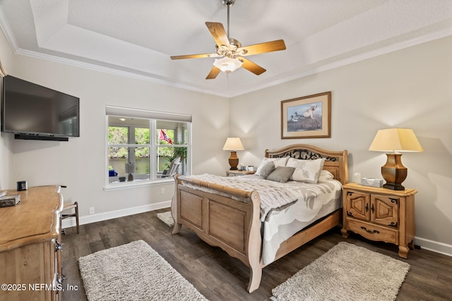 bedroom with dark wood-style flooring, baseboards, ornamental molding, and a raised ceiling