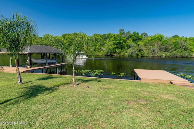 view of dock with a yard and a water view