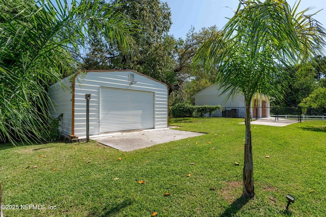 exterior space featuring a patio, fence, an outbuilding, and a detached garage