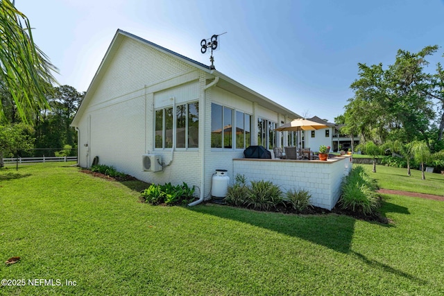rear view of house featuring brick siding, ac unit, fence, and a lawn
