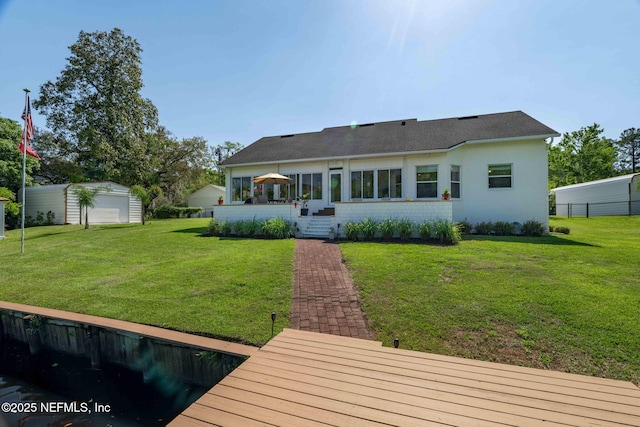 back of property with a yard, brick siding, fence, and an outbuilding