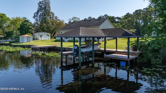view of dock featuring boat lift, a lawn, and a water view