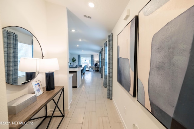 hall with baseboards, visible vents, and recessed lighting