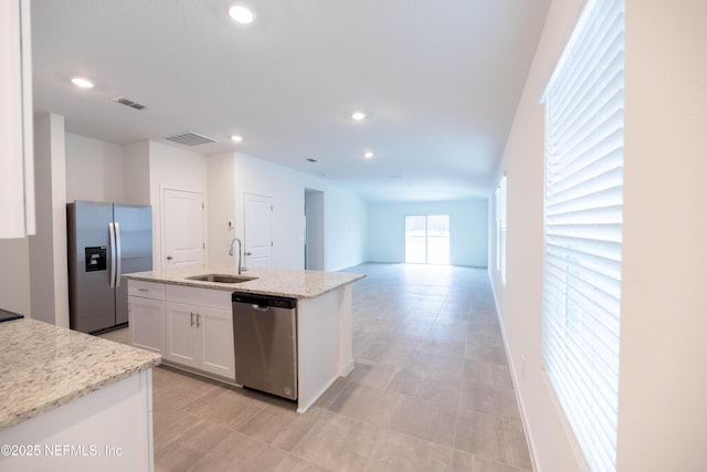 kitchen featuring white cabinets, visible vents, a kitchen island with sink, a sink, and stainless steel appliances