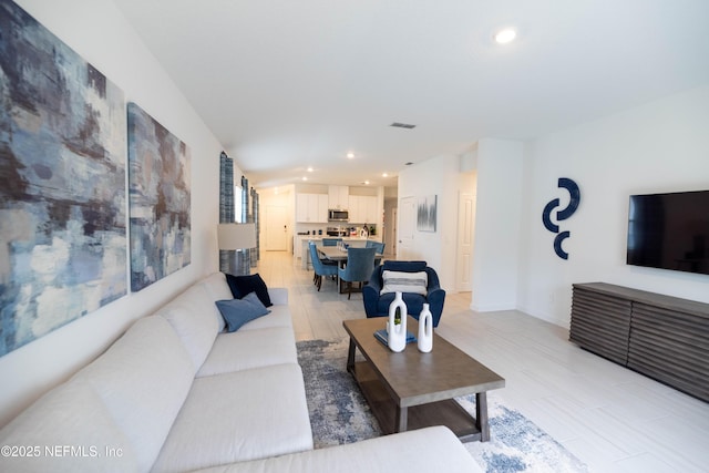 living area with recessed lighting, visible vents, and baseboards