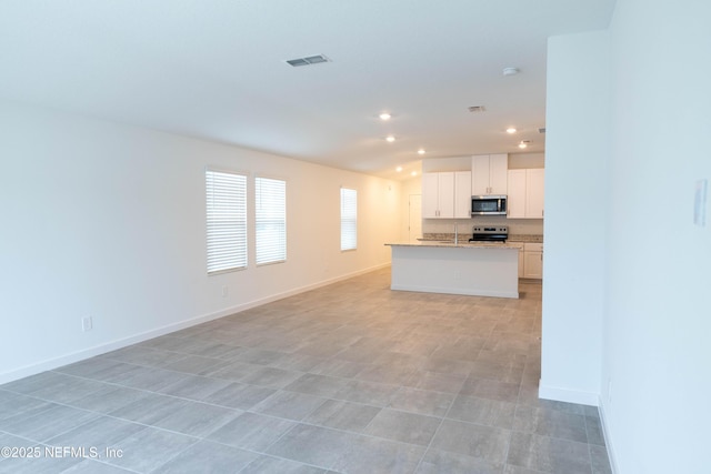 kitchen featuring baseboards, open floor plan, white cabinetry, visible vents, and stainless steel appliances