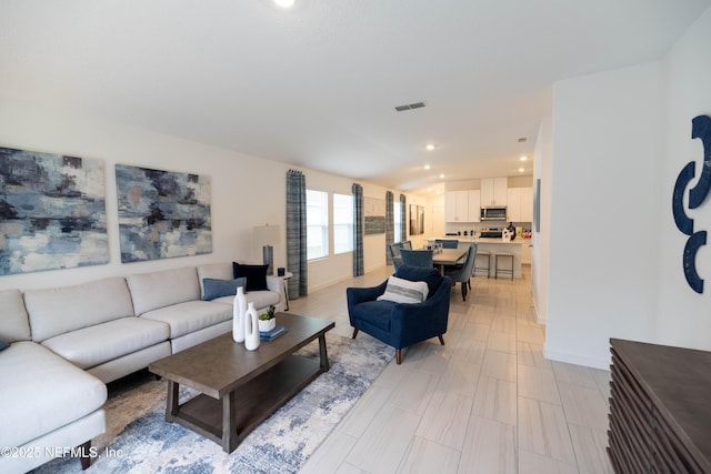 living area with baseboards, visible vents, and recessed lighting