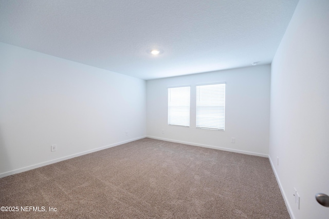 carpeted spare room featuring baseboards