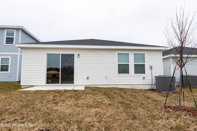 rear view of house with central air condition unit and a lawn