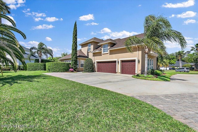 view of front of property with a front yard, a garage, driveway, and stucco siding