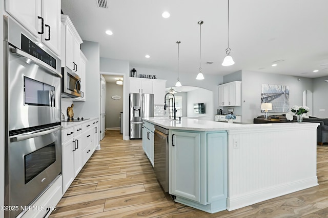 105 Weathered Oak Ct, Saint Johns, FL 32259 - kitchen with appliances with stainless steel finishes, light wood finished floors, light countertops, white cabinets, and a center island with sink