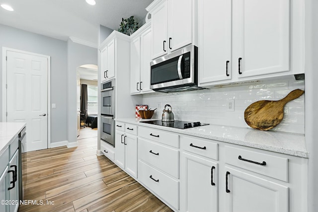 105 Weathered Oak Ct, Saint Johns, FL 32259 - kitchen featuring stainless steel appliances, arched walkways, backsplash, white cabinetry, and light wood-style flooring