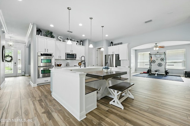 105 Weathered Oak Ct, Saint Johns, FL 32259 - kitchen with stainless steel appliances, a center island with sink, light wood-style floors, white cabinetry, and recessed lighting