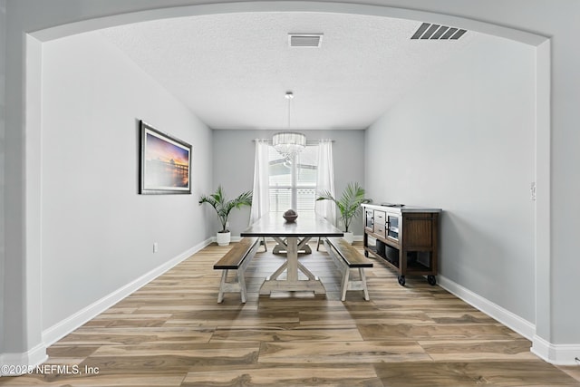 105 Weathered Oak Ct, Saint Johns, FL 32259 - dining space featuring a chandelier, light wood-style floors, a textured ceiling, and arched walkways