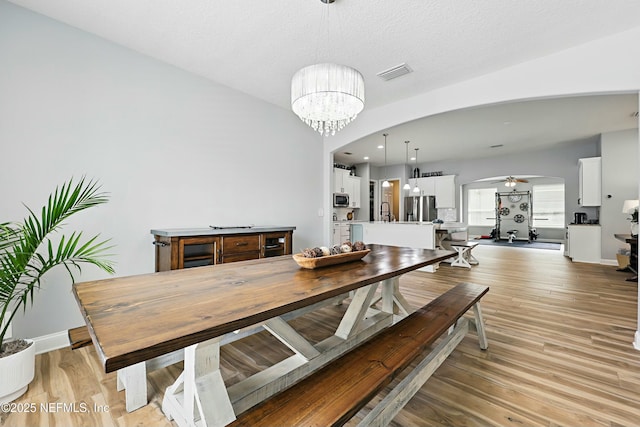105 Weathered Oak Ct, Saint Johns, FL 32259 - dining room with arched walkways, a chandelier, light wood-type flooring, and a ceiling fan