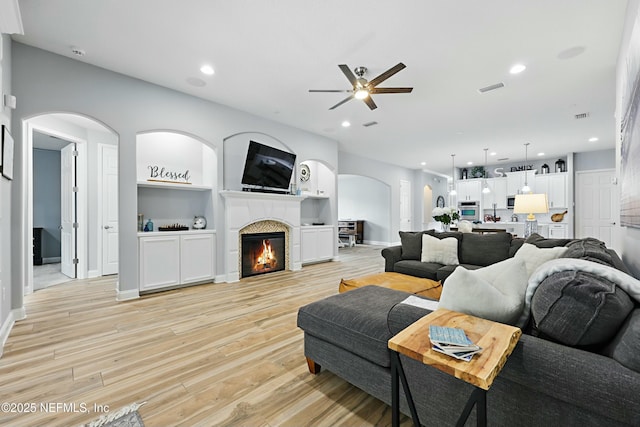 105 Weathered Oak Ct, Saint Johns, FL 32259 - living area with a ceiling fan, light wood-style flooring, arched walkways, recessed lighting, and a glass covered fireplace