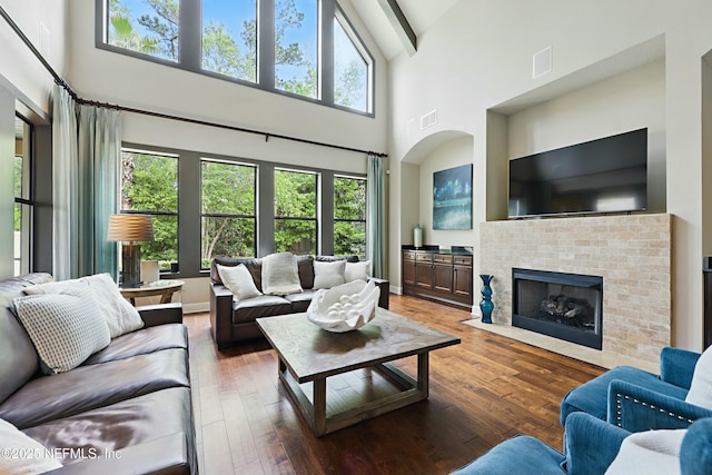 living room featuring hardwood / wood-style floors, high vaulted ceiling, a fireplace, and visible vents